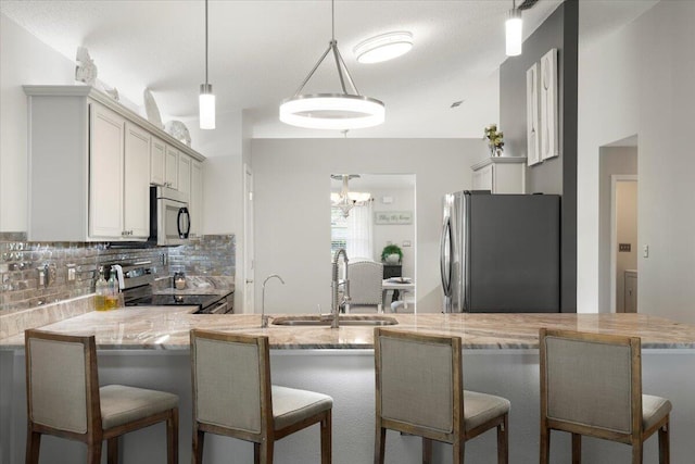 kitchen with tasteful backsplash, decorative light fixtures, stainless steel appliances, and kitchen peninsula