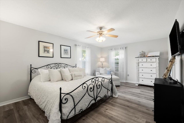 bedroom featuring ceiling fan, dark hardwood / wood-style floors, and a textured ceiling