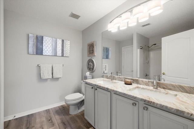 bathroom featuring vanity, hardwood / wood-style floors, toilet, and a textured ceiling