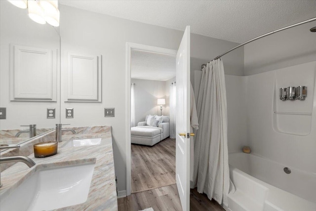 bathroom with vanity, hardwood / wood-style floors, shower / tub combo with curtain, and a textured ceiling