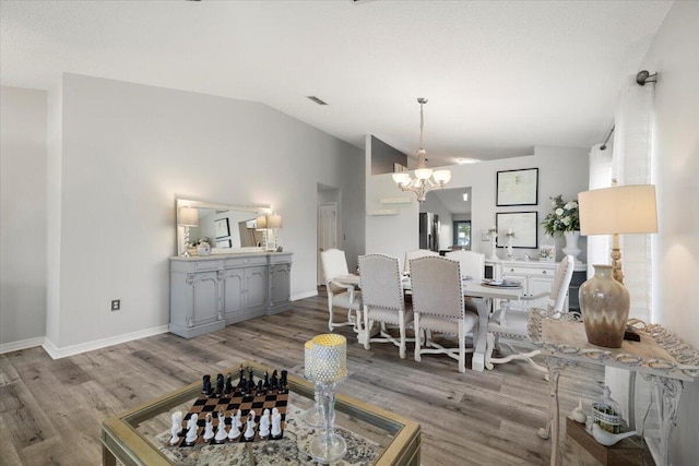 dining area featuring an inviting chandelier, lofted ceiling, and wood-type flooring