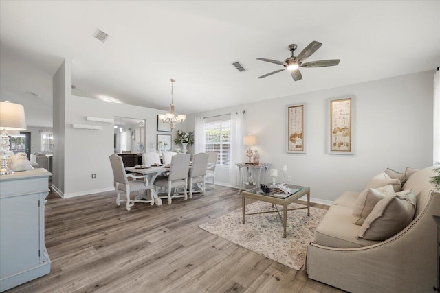 living room with wood-type flooring and ceiling fan with notable chandelier