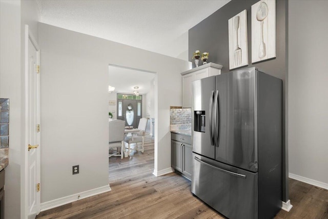 kitchen featuring white cabinetry, hardwood / wood-style floors, stainless steel fridge, and tasteful backsplash