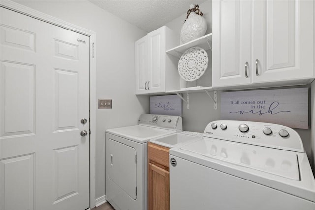 clothes washing area with cabinets, a textured ceiling, and independent washer and dryer