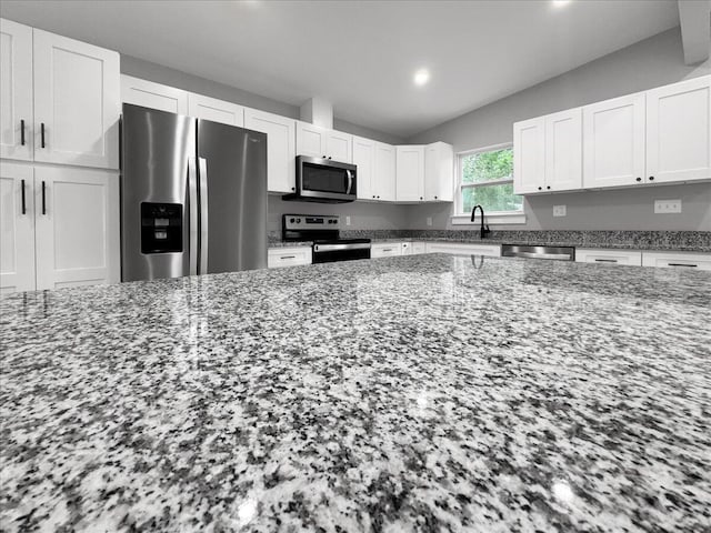 kitchen featuring white cabinetry, appliances with stainless steel finishes, stone countertops, and sink