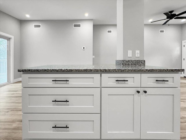 kitchen featuring white cabinetry, stone countertops, ceiling fan, and light wood-type flooring