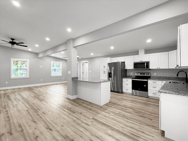 kitchen with lofted ceiling, sink, stone counters, stainless steel appliances, and white cabinets