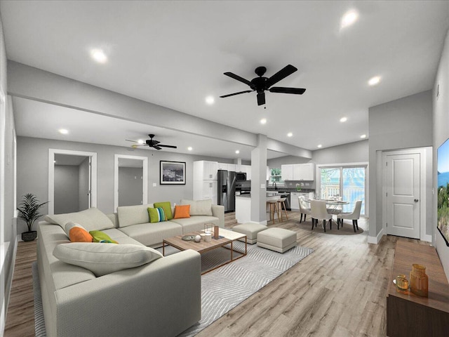 living room with ceiling fan, vaulted ceiling, and light hardwood / wood-style flooring