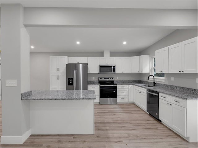 kitchen with white cabinetry, stainless steel appliances, light stone countertops, and sink