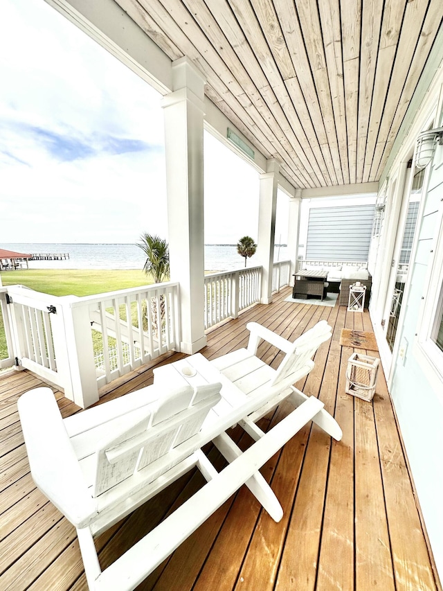 wooden terrace with an outdoor living space and a water view