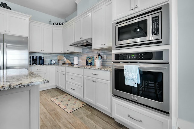 kitchen featuring backsplash, built in appliances, light stone countertops, light wood-type flooring, and white cabinetry