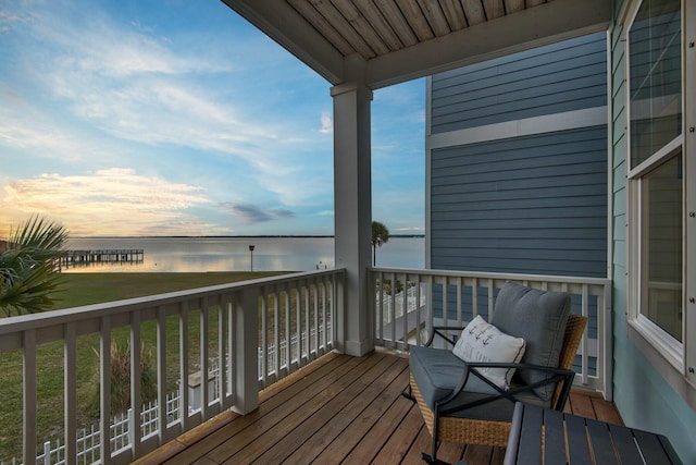 balcony at dusk featuring a water view