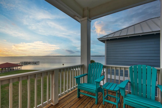 deck at dusk featuring a water view