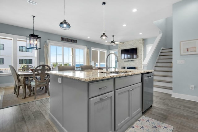 kitchen with gray cabinetry, ceiling fan, dishwasher, sink, and a center island with sink