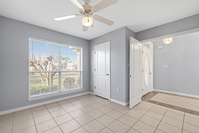 interior space with light tile patterned floors, a textured ceiling, and ceiling fan