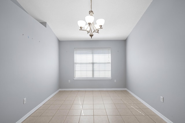 empty room with a notable chandelier, light tile patterned floors, and a textured ceiling