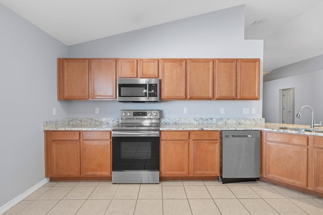 kitchen featuring light stone countertops, sink, stainless steel appliances, lofted ceiling, and light tile patterned floors