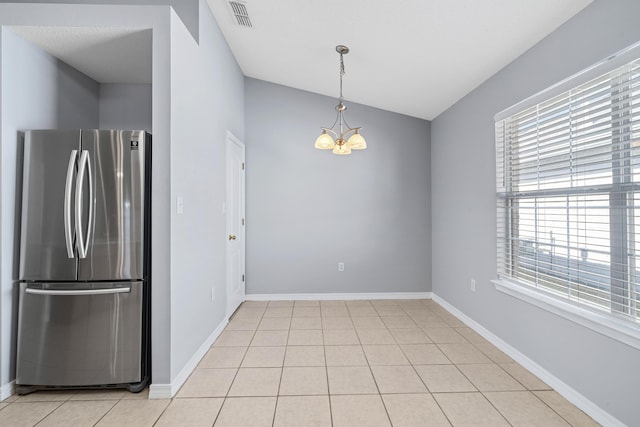 kitchen with stainless steel fridge, light tile patterned floors, decorative light fixtures, an inviting chandelier, and lofted ceiling