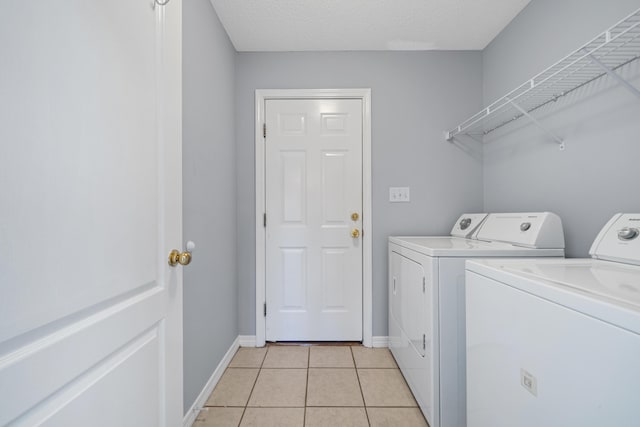 clothes washing area featuring light tile patterned floors, a textured ceiling, and separate washer and dryer