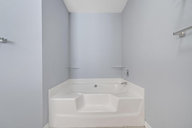 bathroom with a washtub and a textured ceiling