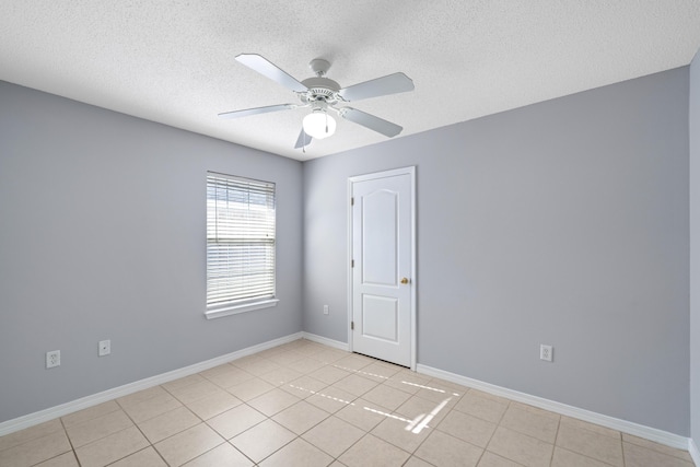 spare room with ceiling fan, light tile patterned floors, and a textured ceiling