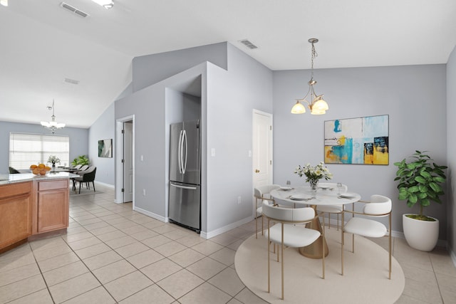 tiled dining space with vaulted ceiling and an inviting chandelier