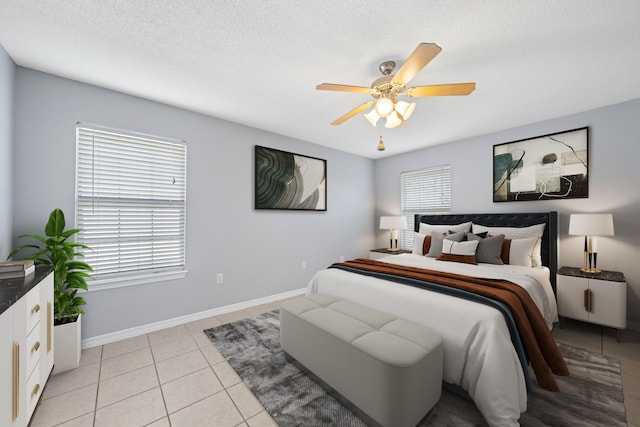 bedroom with multiple windows, light tile patterned floors, a textured ceiling, and ceiling fan