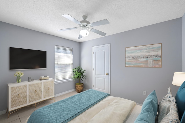 bedroom featuring ceiling fan, light tile patterned floors, and a textured ceiling