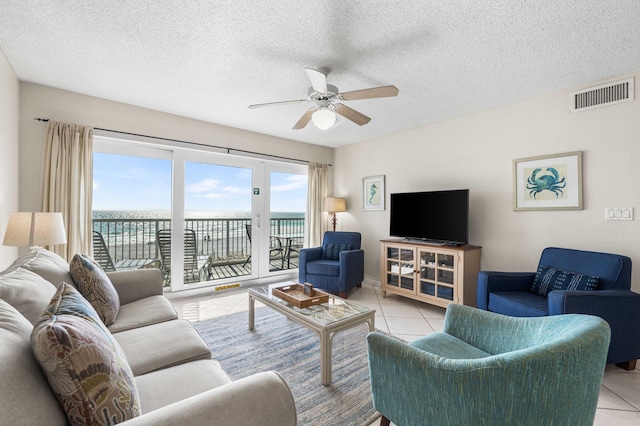 living room with ceiling fan, light tile patterned flooring, and a textured ceiling