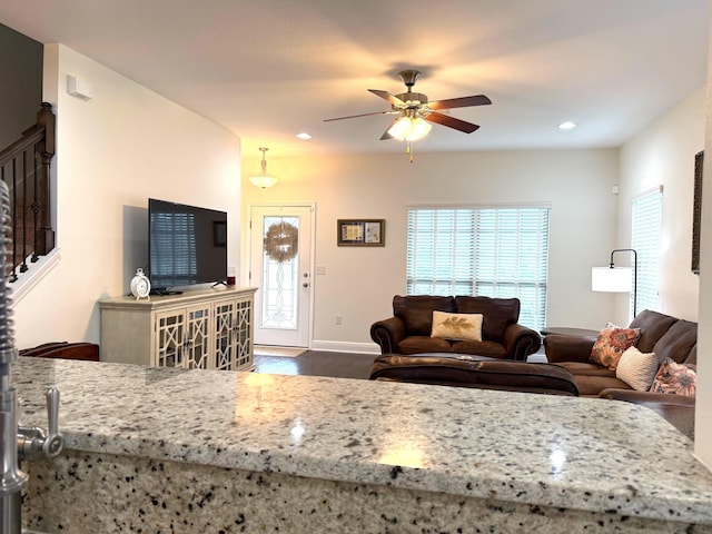 kitchen featuring ceiling fan, dark wood-type flooring, and light stone counters