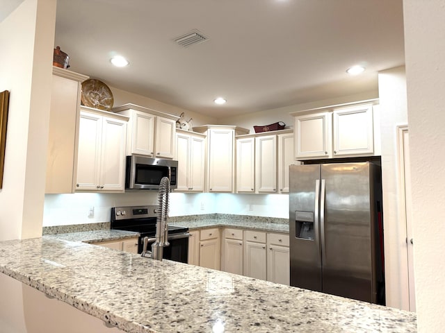 kitchen featuring kitchen peninsula, light stone counters, and stainless steel appliances