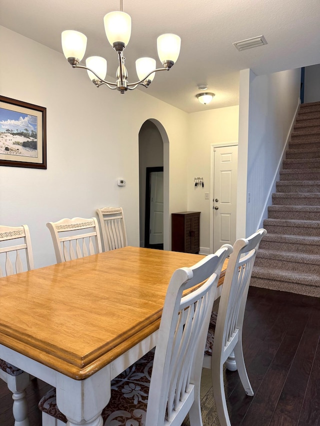 dining area with dark hardwood / wood-style floors and an inviting chandelier