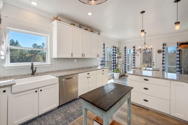 kitchen featuring light stone countertops, stainless steel dishwasher, hanging light fixtures, and sink