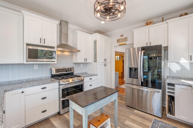 kitchen with light stone countertops, decorative backsplash, stainless steel appliances, wall chimney range hood, and white cabinetry