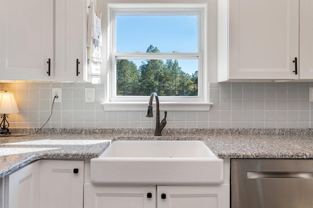 kitchen featuring light stone countertops, tasteful backsplash, white cabinetry, and sink