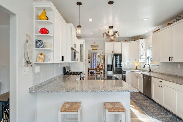 kitchen featuring a breakfast bar, appliances with stainless steel finishes, kitchen peninsula, and white cabinetry