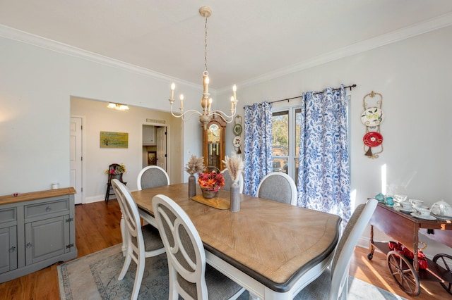 dining space with wood-type flooring, an inviting chandelier, and crown molding