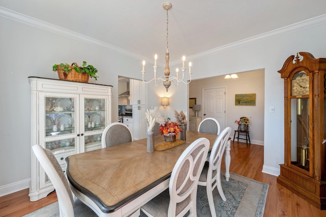 dining room with light wood-type flooring, an inviting chandelier, and ornamental molding