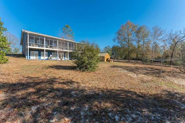 rear view of house featuring a sunroom and a storage unit