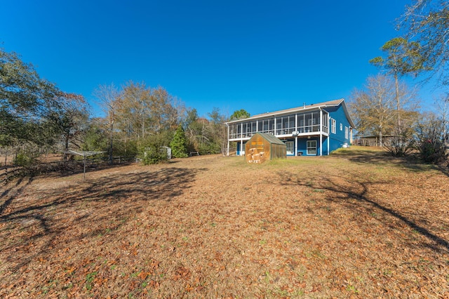 rear view of property featuring a sunroom, an outbuilding, and a yard