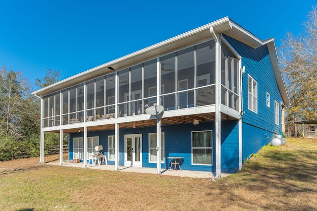 back of property featuring a sunroom, a patio area, and a lawn