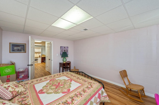 bedroom featuring a drop ceiling and wood-type flooring