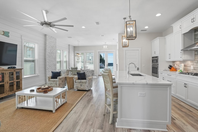 kitchen with white cabinetry, a kitchen island with sink, and pendant lighting