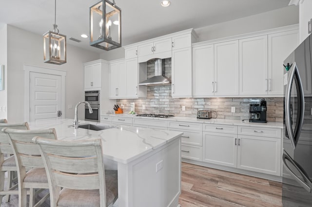 kitchen with hanging light fixtures, white cabinets, stainless steel appliances, and wall chimney range hood