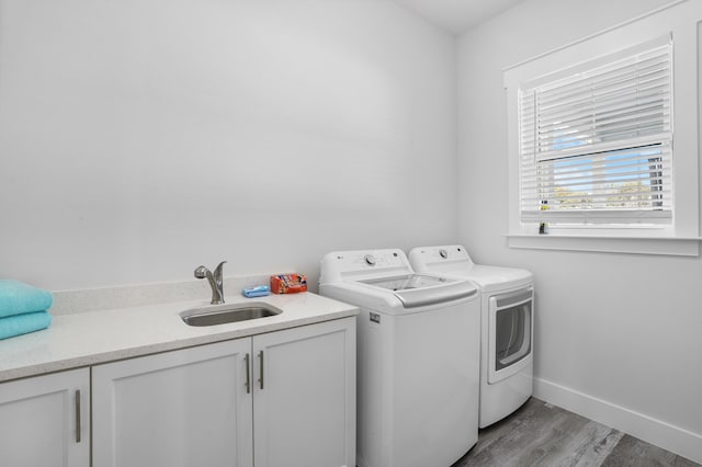 laundry room featuring separate washer and dryer, sink, cabinets, and light hardwood / wood-style floors