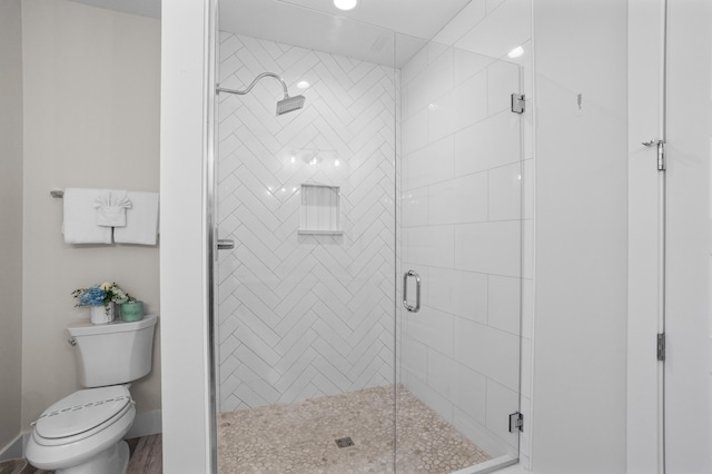 bathroom with a shower with shower door and toilet