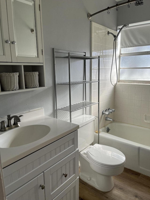 full bathroom with vanity, tiled shower / bath, hardwood / wood-style flooring, and toilet