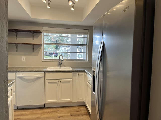 kitchen with dishwasher, stainless steel refrigerator with ice dispenser, a tray ceiling, white cabinets, and sink