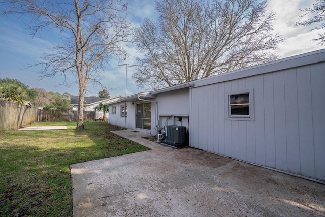 view of side of property with a lawn, central AC unit, and a patio area