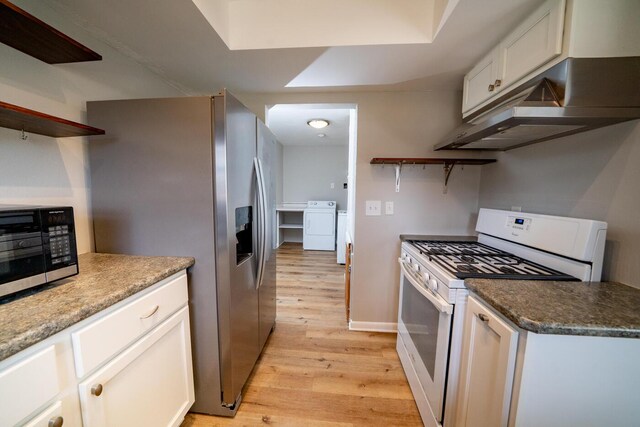 kitchen featuring washing machine and clothes dryer, light hardwood / wood-style flooring, a tray ceiling, stainless steel appliances, and white cabinets